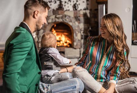 Young happy family together in interior of house with fireplace.の写真素材