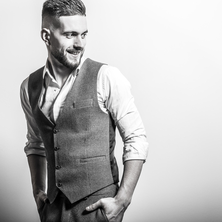 Handsome young elegant man in grey classic vest pose against studio background.の写真素材