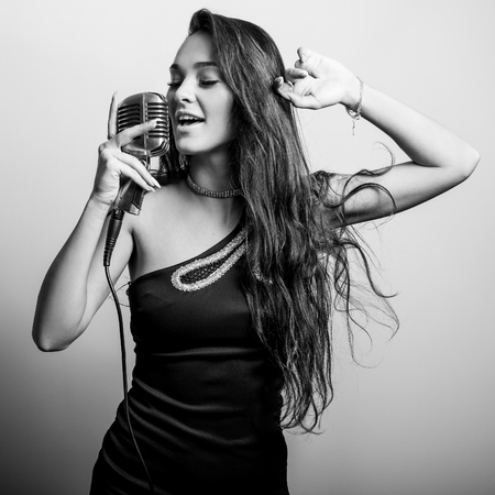 Young sensual woman in black dress with microphon. Black-white portrait.の写真素材