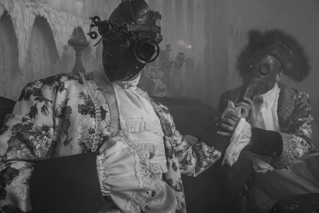 Actors in steam punk masks and antique costumes indoor. Black-white photo.の写真素材
