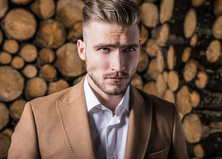 Portrait of young beautiful fashionable man in coat against wooden background.の写真素材