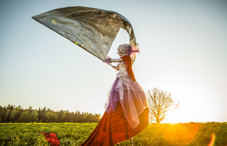 Fairy tale woman on stilts with silver flag in bright fantasy stylization. Fine art outdoor photo. の写真素材