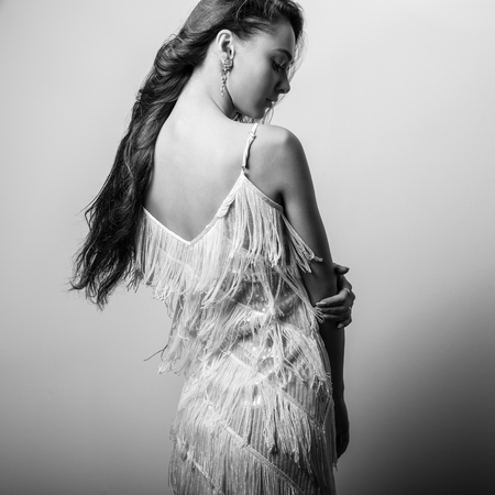 Young beautiful woman in white dress black-white studio portrait.