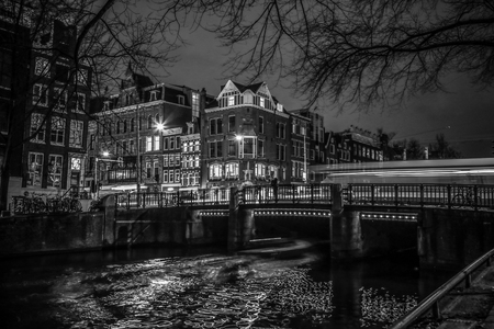 AMSTERDAM, NETHERLANDS - JANUARY 08, 2017: Trams drives by old bridge in Amsterdam city at night. January 08, 2017 in Amsterdam - Netherland.のeditorial素材