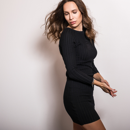 Beautiful girl in stylish black dress posing in studio.の写真素材