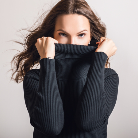 Beautiful girl in stylish black dress posing in studio.の写真素材