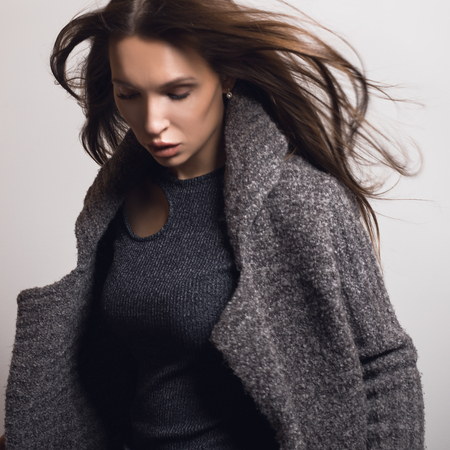 Beautiful young girl in gray coat posing in studio.の写真素材