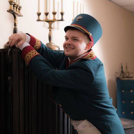 Actor dressed historical costume in interior of old theater.