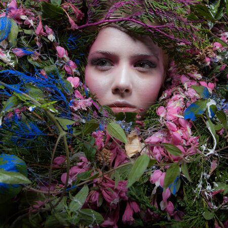 Female portrait in fairy tale stylisation surrounded with natural plants and flowers.の写真素材