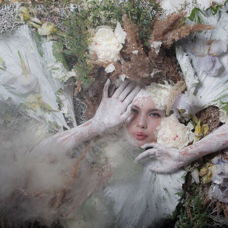 Female portrait in fairy tale stylisation surrounded with natural plants and flowers.の写真素材