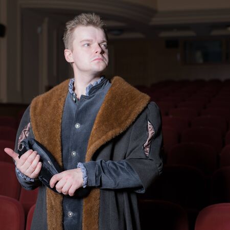 Actor dressed historical costume in interior of old theater.