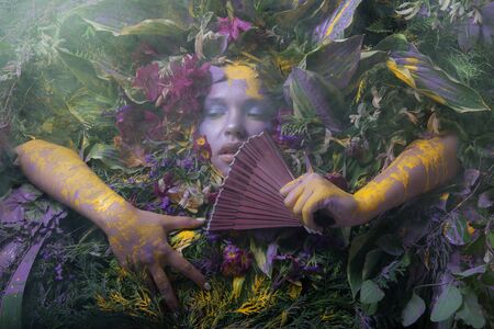 Female portrait in fairy tale stylisation surrounded with natural plants and flowers.の写真素材