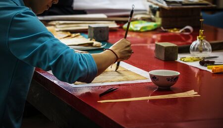 BEIJING, Ð¡HINA - JUNE 01, 2019: Traditional Chinese book and calligraphy restorer laboratory. Master hands at work close-up.のeditorial素材