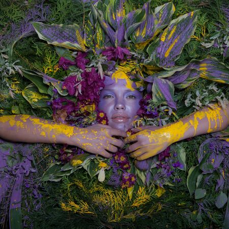 Female portrait in fairy tale stylisation surrounded with natural plants and flowers.
