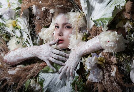 Female portrait in fairy tale stylisation surrounded with natural plants and flowers.の写真素材