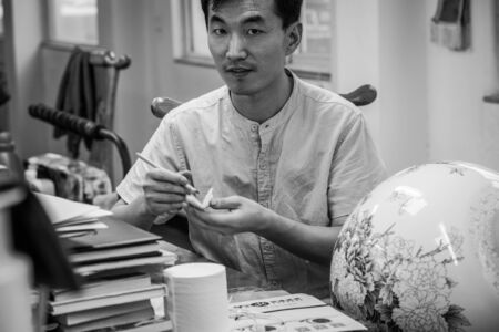 BEIJING, Ð¡HINA - JUNE 03: Chinese craftsman paints a large porcelain vase with traditional tassels. Master hands close-up.のeditorial素材