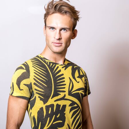 Elegant young handsome man in yellow T-shirt. Studio portrait.の写真素材