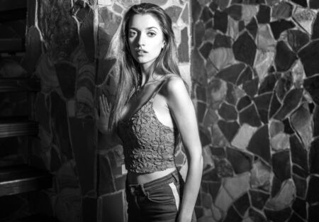 Young beauty woman against natural stone background. Black-white portrait.の写真素材