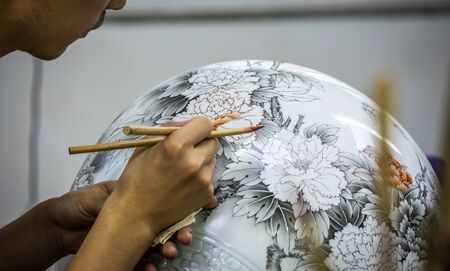 BEIJING, Ð¡HINA - JUNE 03: Chinese craftsman paints a large porcelain vase with traditional tassels. Master hands close-up.のeditorial素材