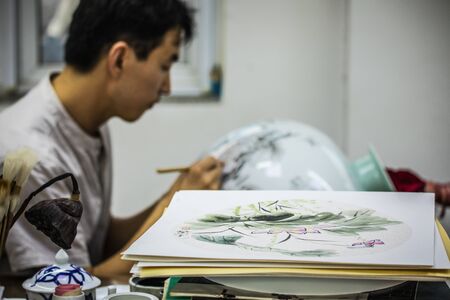 BEIJING, Ð¡HINA - JUNE 03: Chinese craftsman paints a large porcelain vase with traditional tassels. Master hands close-up.のeditorial素材