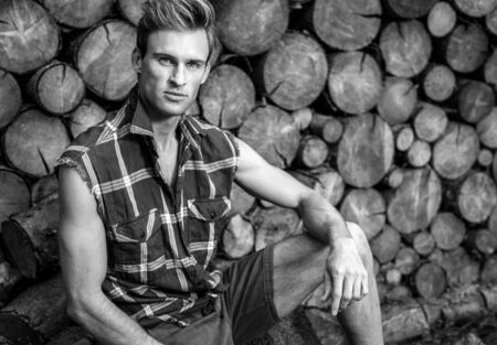 Young handsome man in casual shirt poses near wooden background. Black-white photo.の写真素材