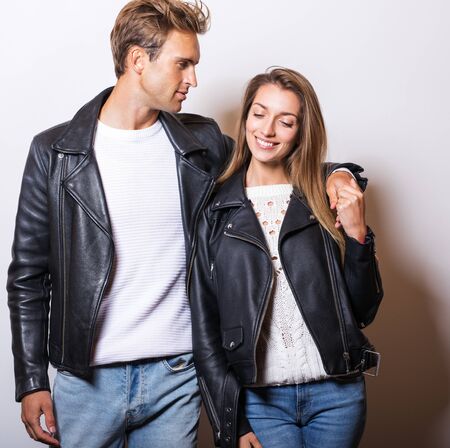 Young beautiful couple in black leather jackets pose in studio.の写真素材
