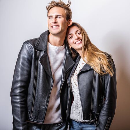 Young beautiful couple in black leather jackets pose in studio.の写真素材