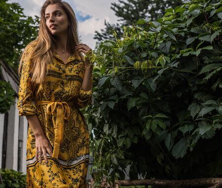 Beautiful emotional outdoor portrait of young woman in yellow dress.の写真素材