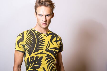 Elegant young handsome man in yellow T-shirt. Studio portrait.の写真素材