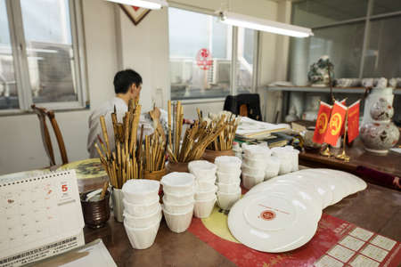 BEIJING, Ð¡HINA - JUNE 03: Chinese craftsman paints a large porcelain vase with traditional tassels. Master hands close-up.のeditorial素材