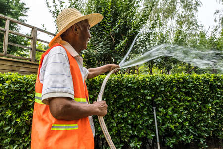 BEIJING, Ð¡HINA - JUNE 01, 2019: Old Chinese smiling man watering garden.のeditorial素材