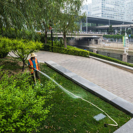 BEIJING, Ð¡HINA - JUNE 01, 2019: Old Chinese smiling man watering garden.のeditorial素材