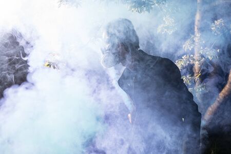 Young man portrait in mask with degree of protection posing in twilight of spring garden.