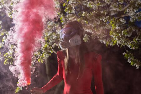 Young beautiful girl portrait in a mask with degree of protection posing in twilight of spring garden.の写真素材
