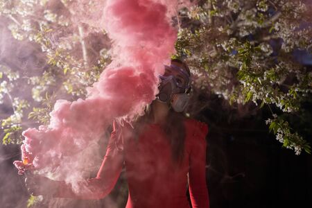 Young beautiful girl portrait in a mask with degree of protection posing in twilight of spring garden.の写真素材