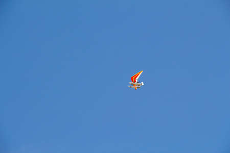 ultra light motorized hang-glider flying in the blue sky 