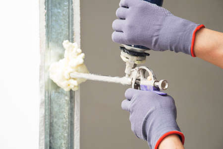 Installing door unit. Workman fixing the door frame using a mounting foamの写真素材