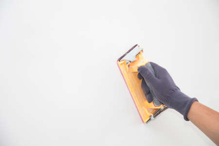 hand grinding with sandpaper on a white wallの写真素材
