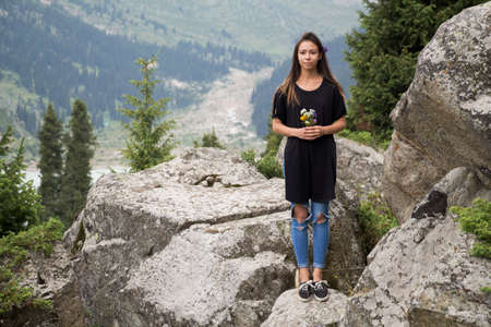 Beautiful girl holding in hands beautiful wildflowers in mountainsの写真素材