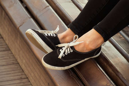 female legs in sneakers on the bench