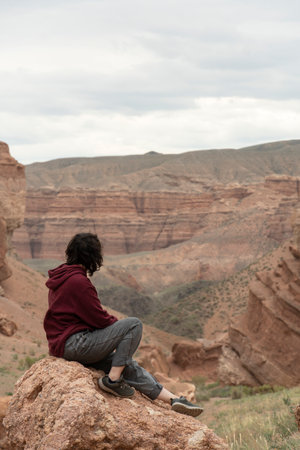 A young woman sits on a rock in the Central Asian Grand Canyonの写真素材
