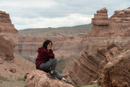 A young woman sits on a rock in the Central Asian Grand Canyonの写真素材