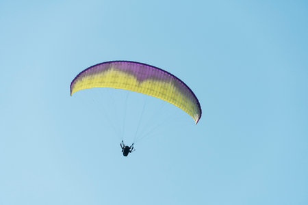 Beautiful picture of a paraglider gliding on a clear blue sky.