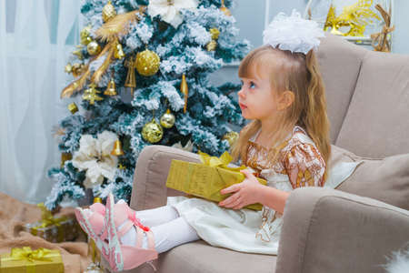 Festive little girl opening a gift at home in the living roomの写真素材