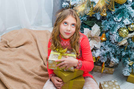 Festive little girl opening a gift at home in the living roomの写真素材