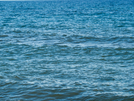Blue sea water texture background. Sea surface with waves and foam.の写真素材
