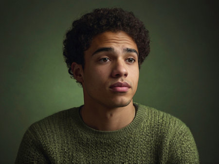 portrait of a young latin man in a green sweater on a dark backgroundの素材