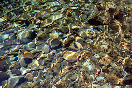 Background of river rocks, with some light efects on the water.