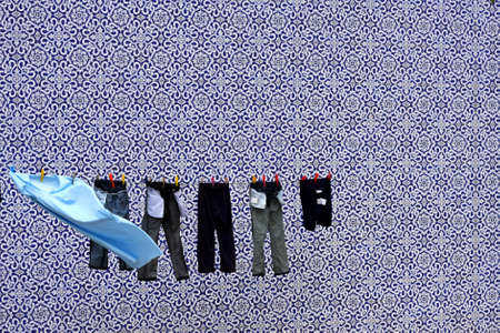 A detail of clothes drying in the sun, over a background of azulejo tiles.の写真素材