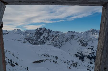 View through ancient door in the mountains in winter at Nebelhorn, Germanyの写真素材